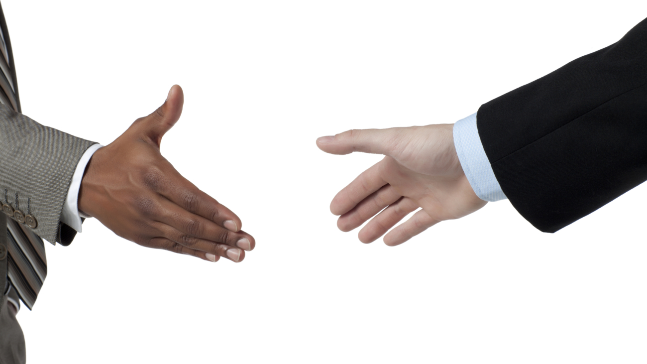 Two business people about to hand shake isolated on a white surface